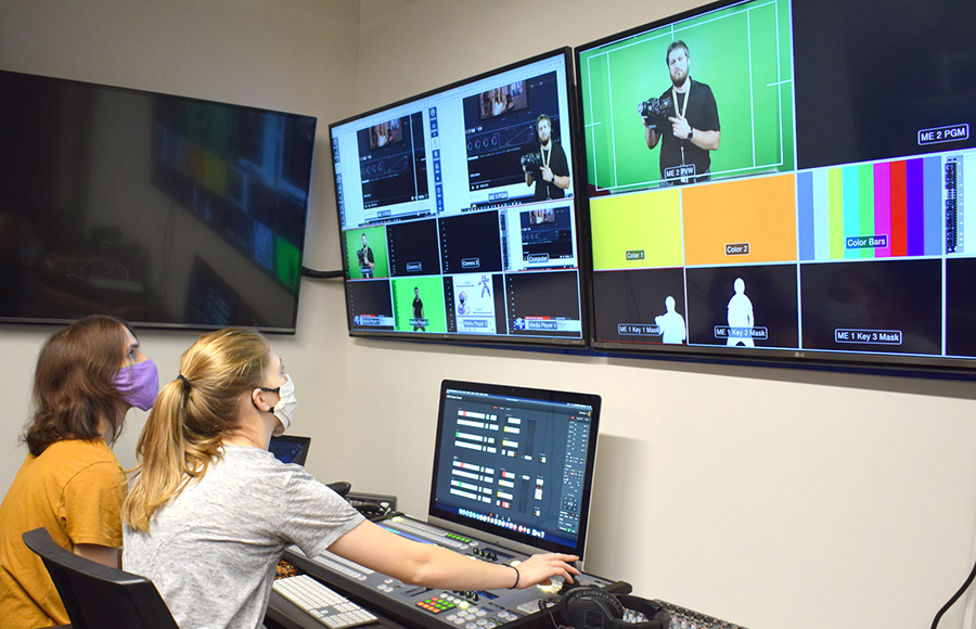 Two students work the control panel in an interactive lab.