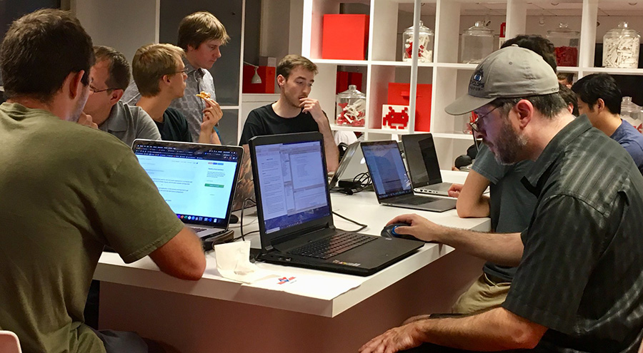 Group of students work on computers around a table.