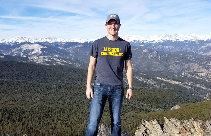 Isaac Lagermann stands in front of a mountain range.