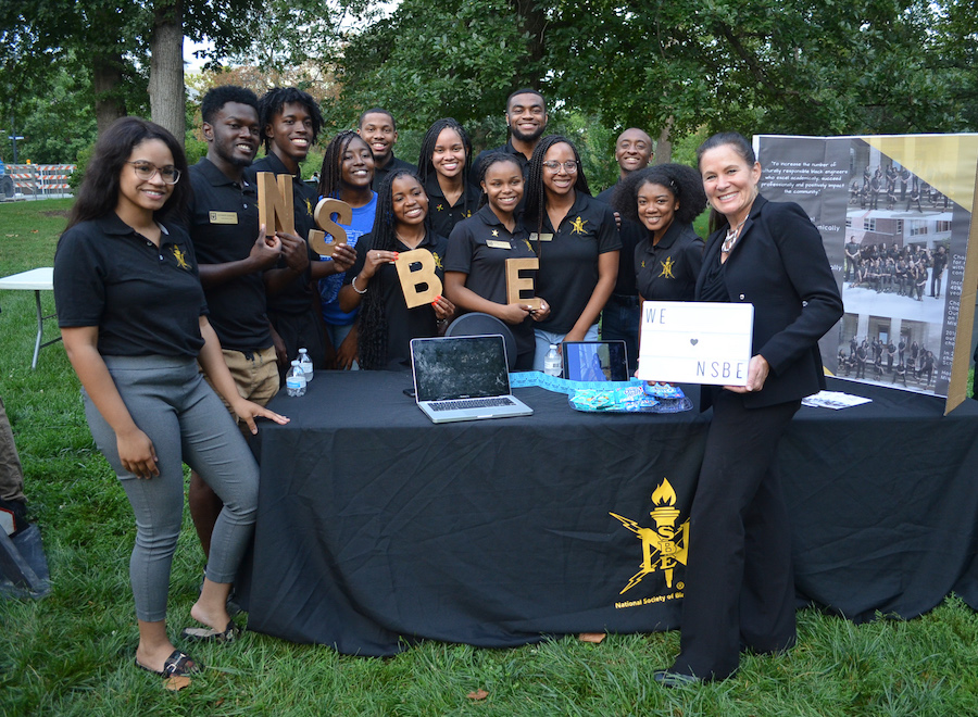 Dean Loboa poses with a group of students holding signs representing NSBE.