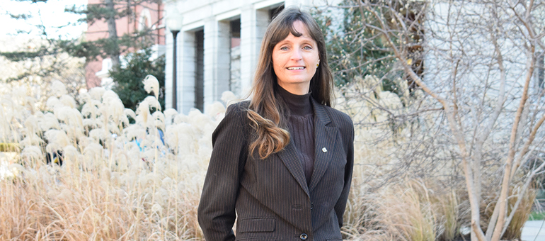 Sheila Grant poses in front of some foliage.