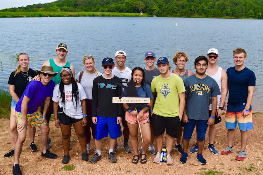 Students pose for a photo on the shore of a lake.