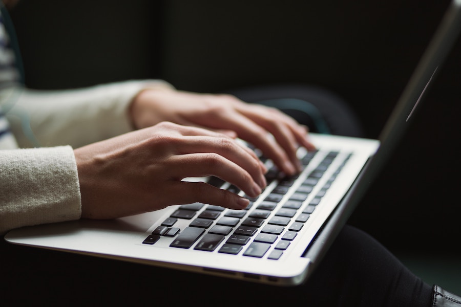 Hands typing on a laptop keyboard