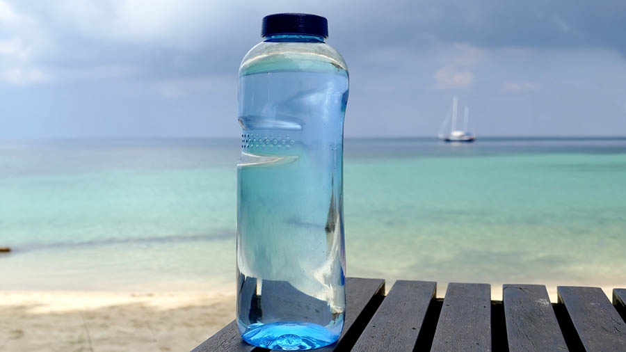 Bottle of water on table in front of ocean.