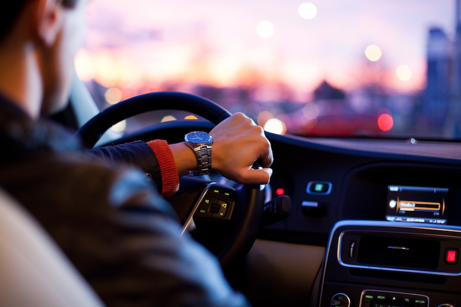 Looking over the shoulder of a person driving a car at sunset.