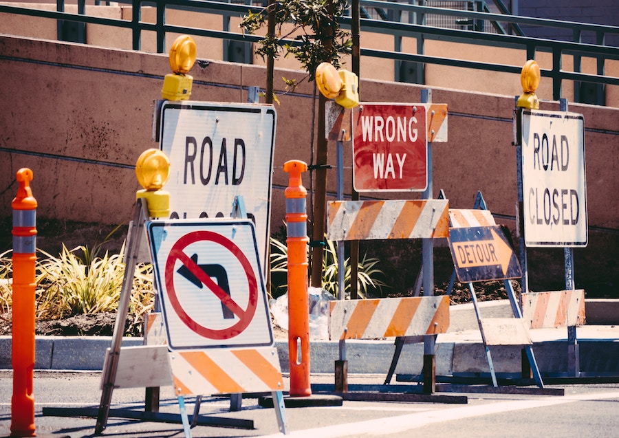 Various road signs closing off a street. They read 