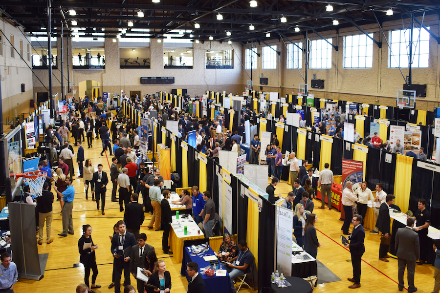 Shown from above: the basketball courts at the Rec Center, filled with black and gold employer booths and students dressed for success.