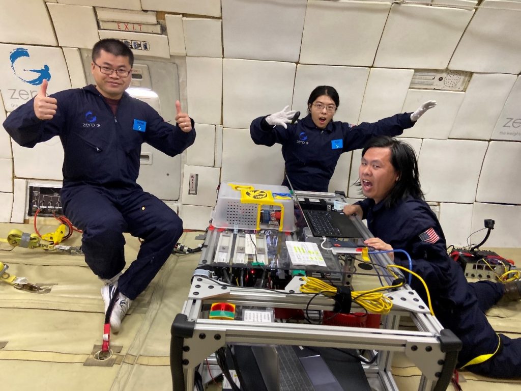 Members of the team floating in zero gravity and giving thumbs-up