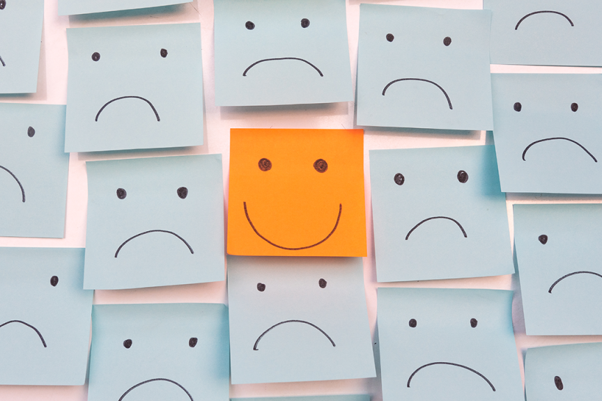 Sticky notes with sad faces and happy face in center.