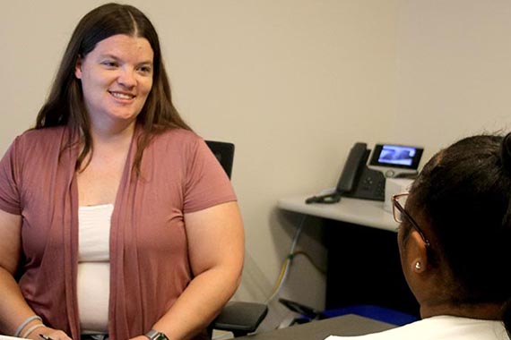 Woman at desk speaking to a student